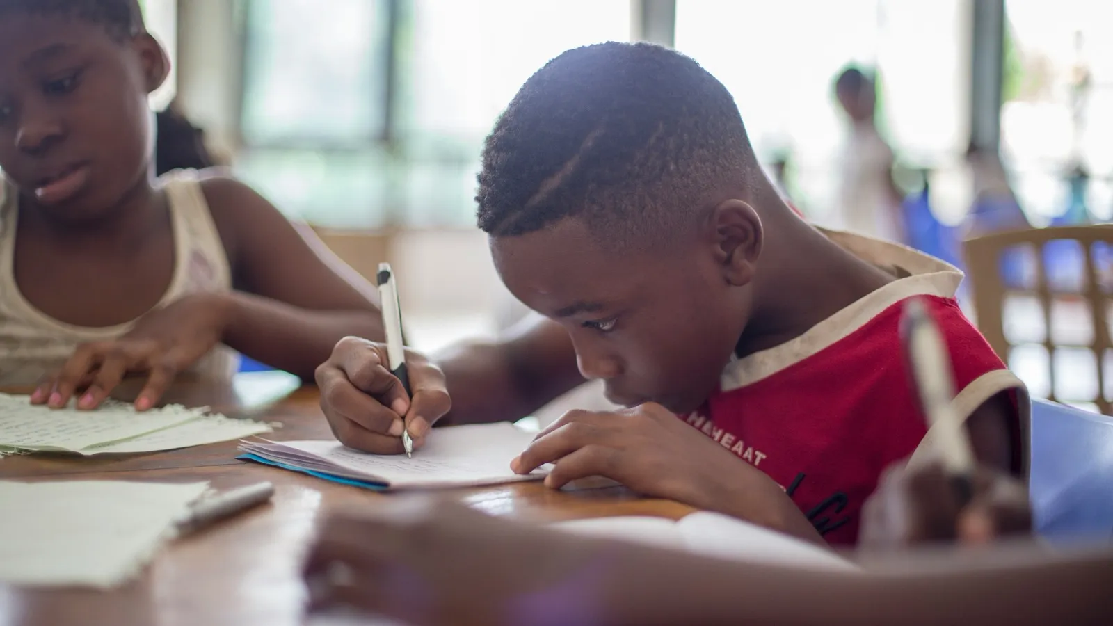 A child writing at a table, focused on their work